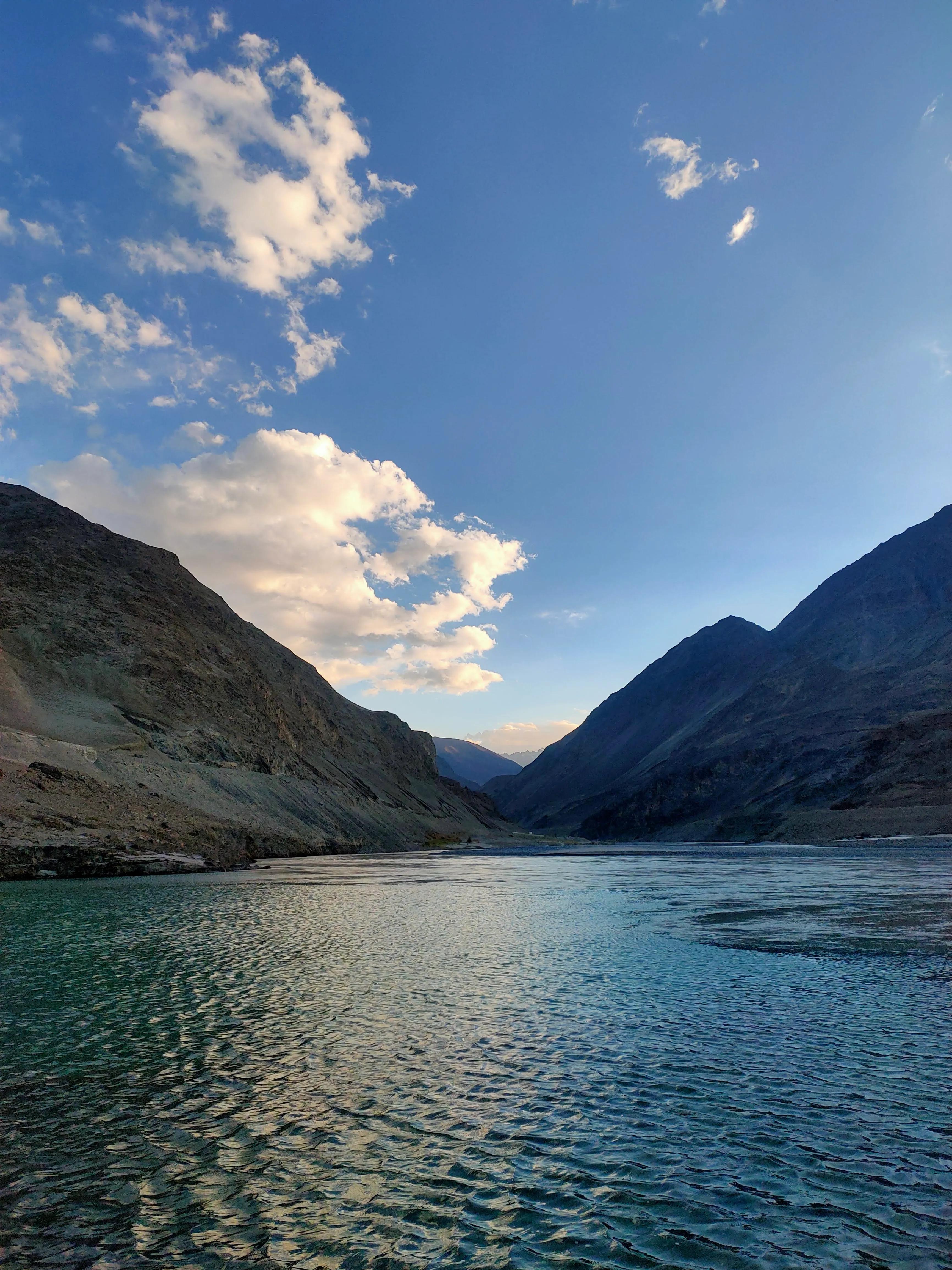 A wide river flowing between steep rocky mountains under a blue sky